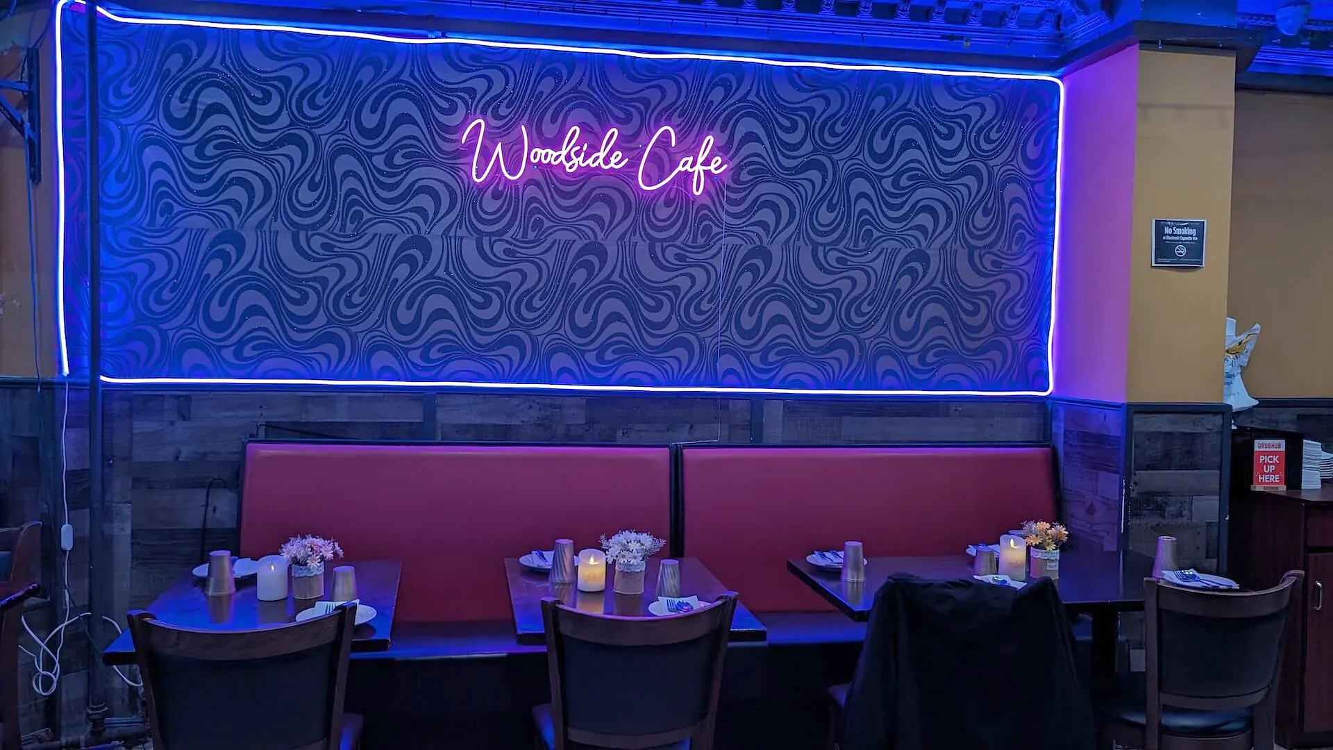 The restaurant’s name in script neon above the back-wall banquettes