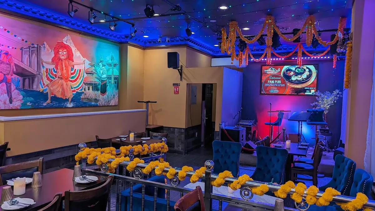 The dining room at night, marigold garlands overhead and the Lakhey mural along the far wall