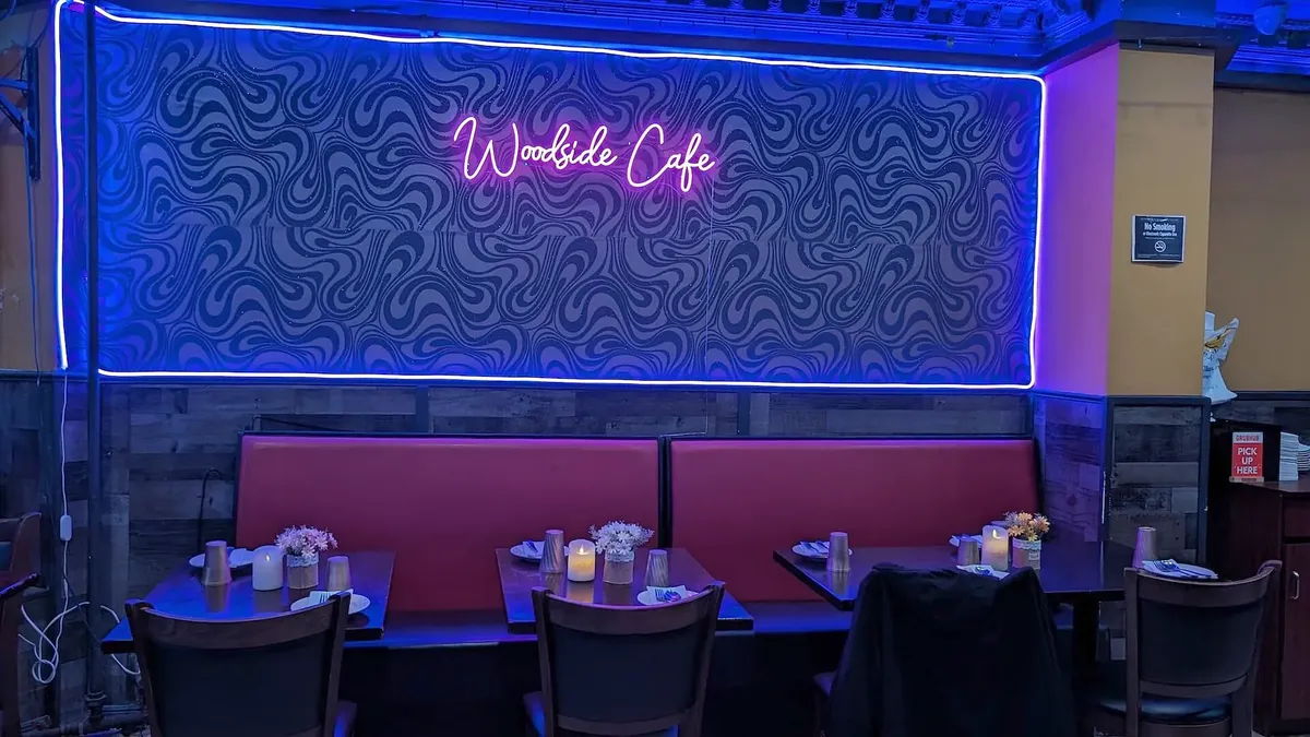 The restaurant’s name in script neon above the back-wall banquettes