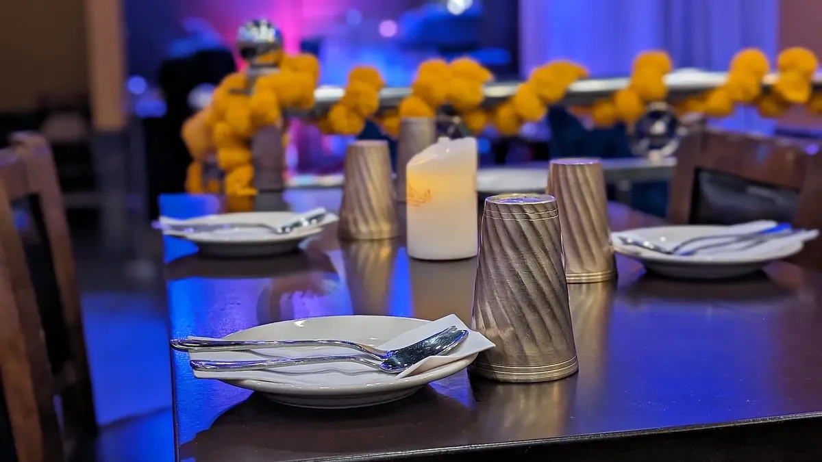 A laid table — plates, a candle, marigolds behind