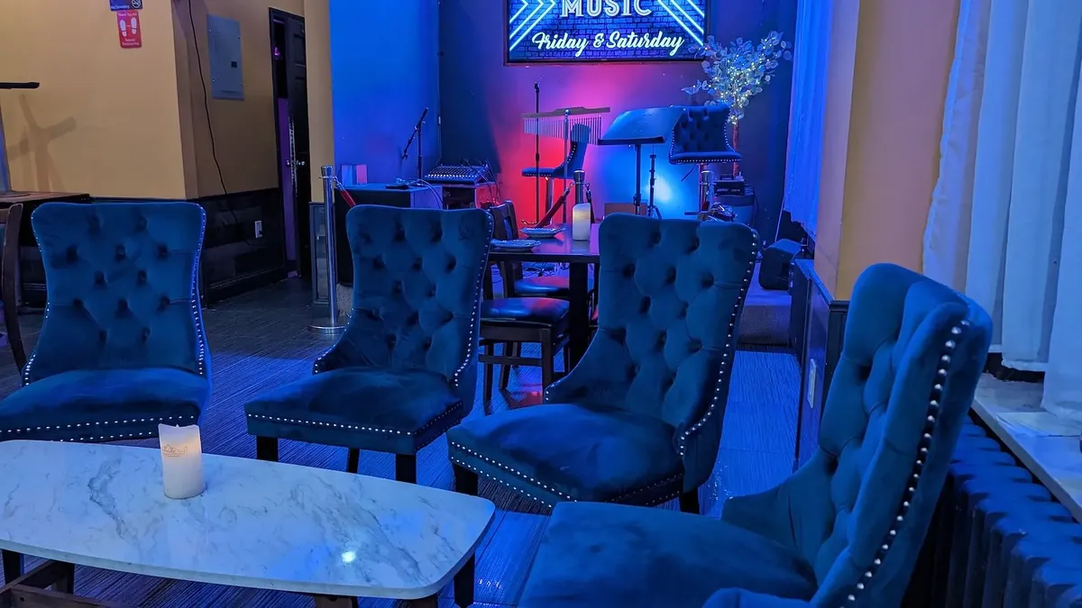 Blue velvet wing chairs beside the stage, under the live-music sign