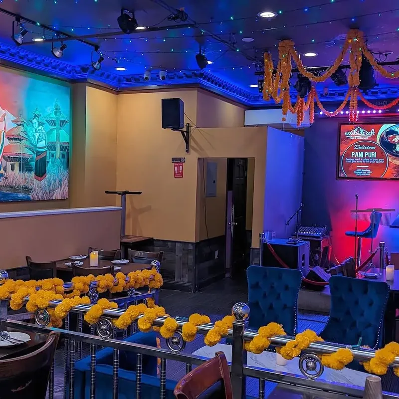 The dining room at night, marigold garlands overhead and the Lakhey mural along the far wall