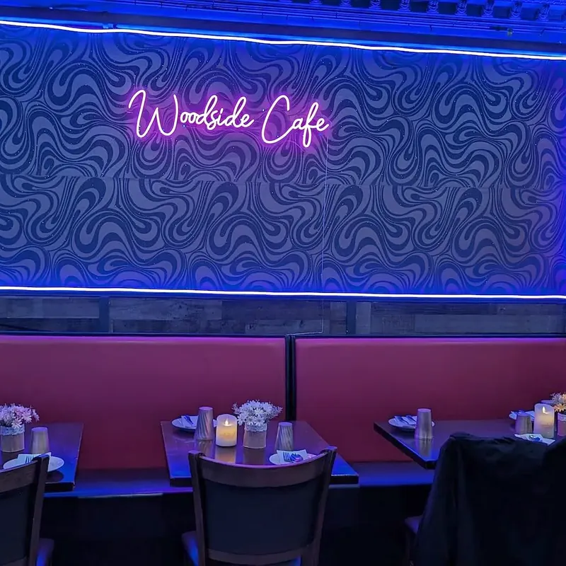 The restaurant’s name in script neon above the back-wall banquettes
