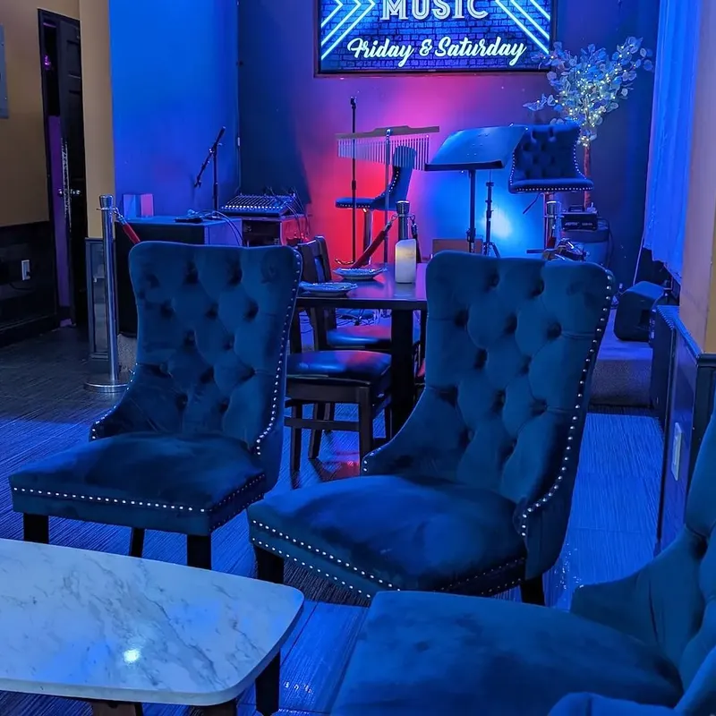 Blue velvet wing chairs beside the stage, under the live-music sign